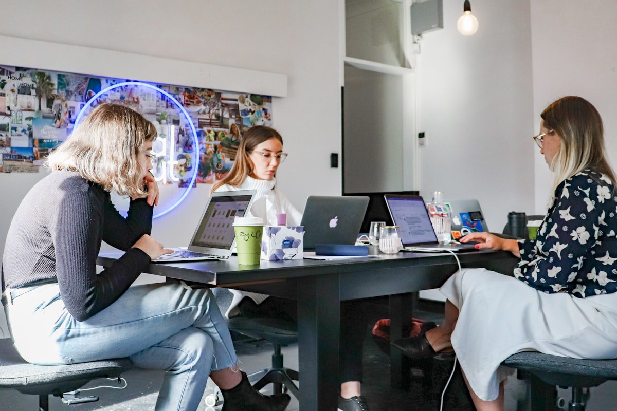 Team of professionals collaborating around laptops, representing the new wave of agentic AI jobs emerging in 2026
