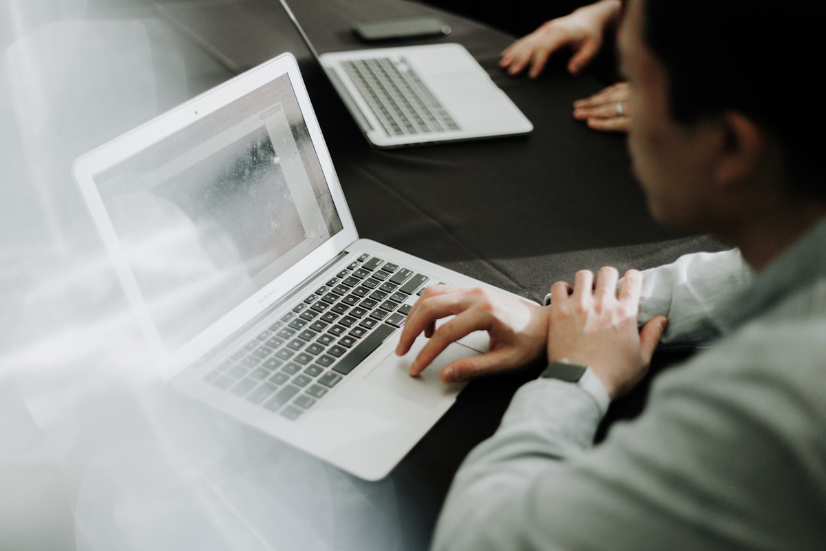 Two professionals reviewing a resume and job description on laptops for ATS keyword optimization
