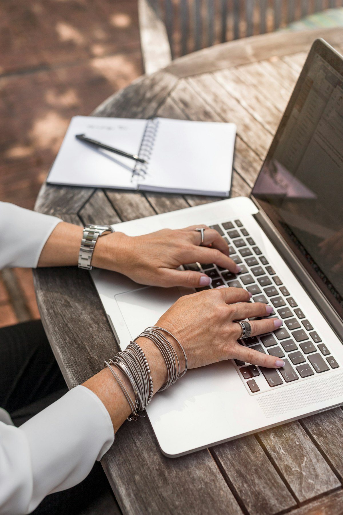 Person typing on a laptop next to a notebook, representing documenting agentic AI experiments and learning publicly