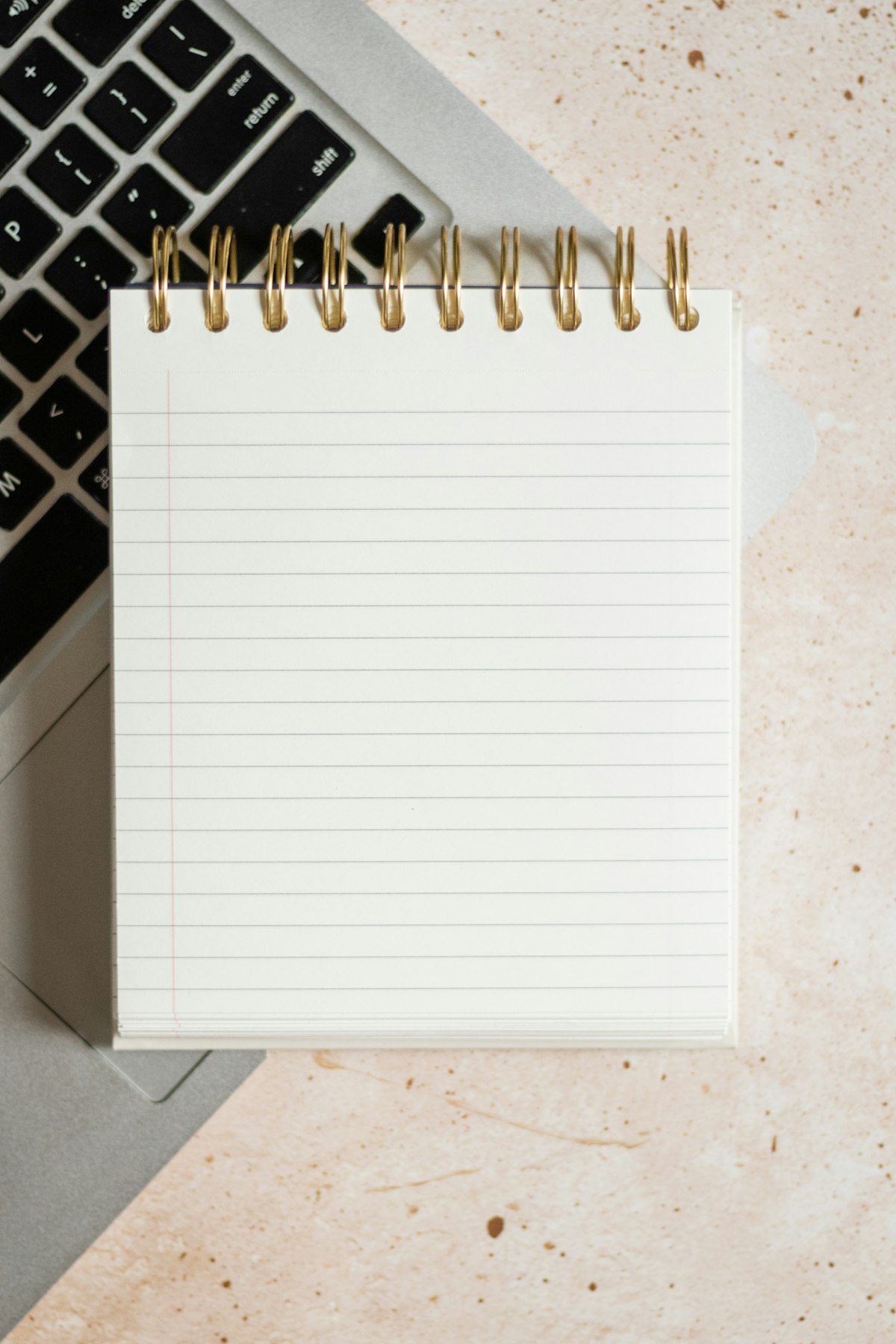 Blank spiral notebook beside a laptop keyboard, representing Claude AI as a free writing alternative to paid AI writers