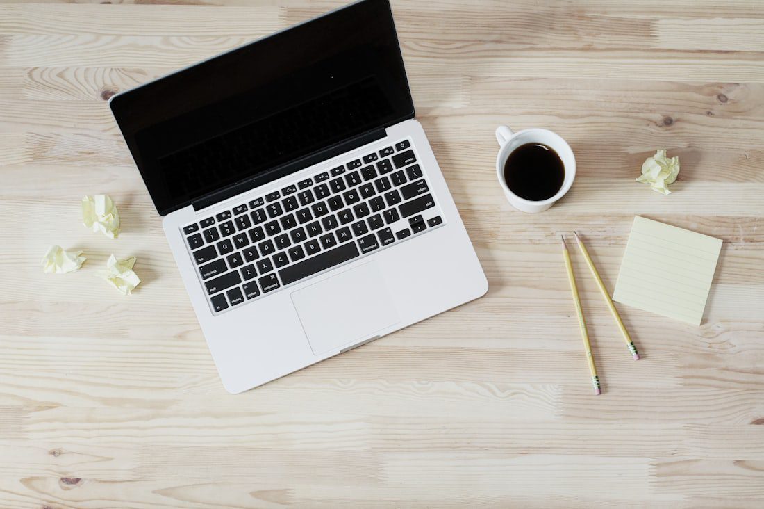 Laptop on a desk with coffee and notepad, representing signing up for a free Google Ads account